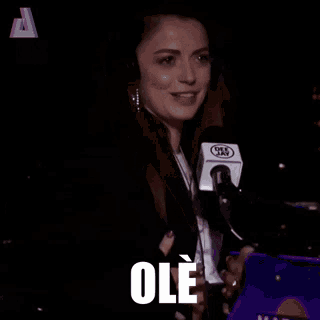 a woman wearing headphones and holding a microphone with the word ole on it .