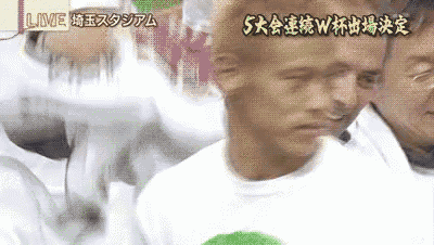 a man in a white shirt is standing in front of a crowd with chinese writing on the bottom of the screen .