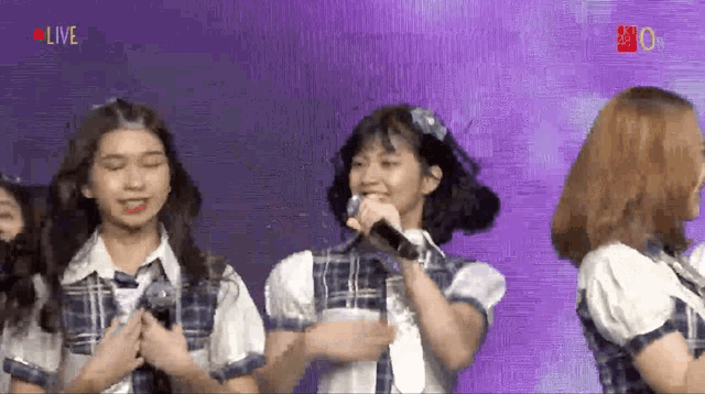a girl singing into a microphone with the word live in the upper right corner