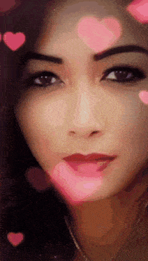 a close up of a woman 's face with pink hearts surrounding her