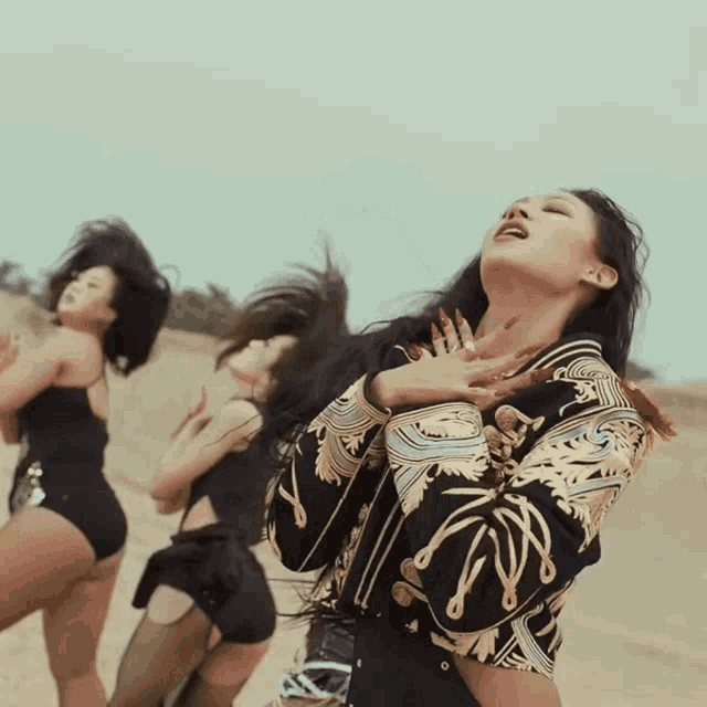 a woman in a black and gold jacket is dancing with her hands on her chest