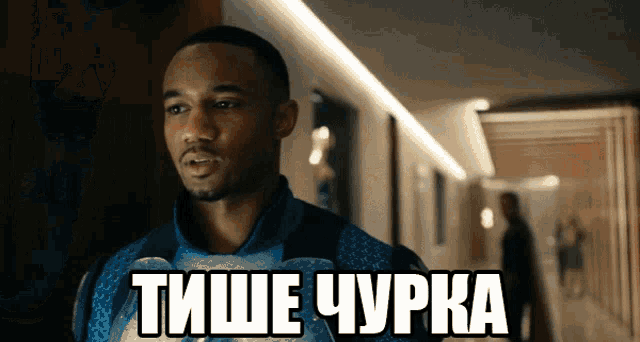 a man in a blue shirt is standing in a hallway with a caption that says " тише чурка " on it