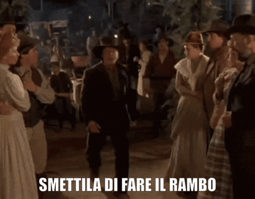 a group of people standing in a crowd with smettila di fare il rambo above them