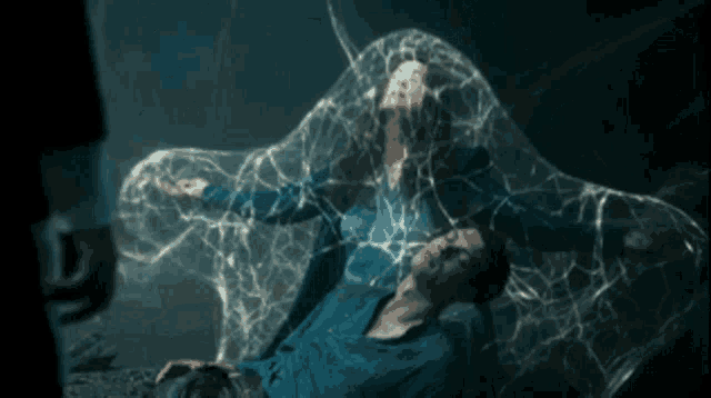 a man and a woman are laying on a bed with a spider web around them