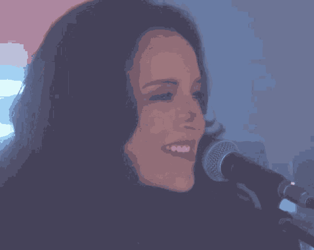 a woman sings into a microphone with her eyes closed