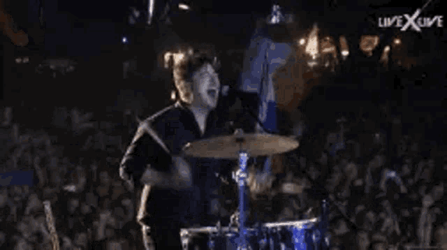 a man is playing drums on a stage in front of a crowd .