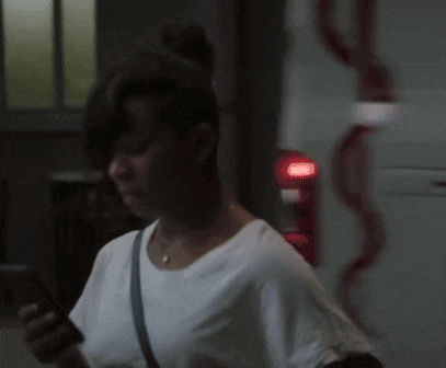 a woman in a white shirt is looking at her phone in front of an ambulance