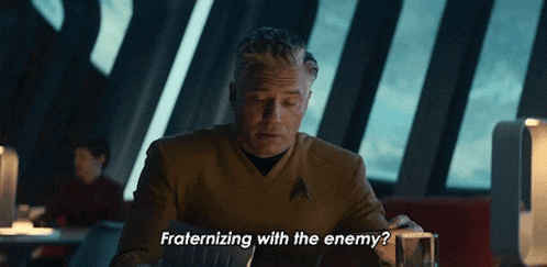 a man sitting at a table with the words " fraternizing with the enemy " below him