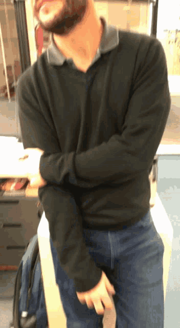 a man with a beard wearing a black shirt and blue jeans