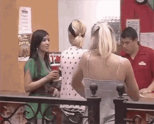 a group of women are standing next to each other in a restaurant talking to a man .