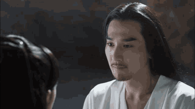 a man with long hair and a beard is looking at a woman with a beard .