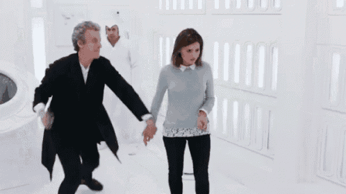 a man and a woman are standing next to each other in a room with white walls .
