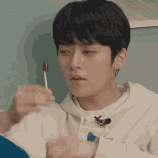 a young man is holding a lollipop in front of his face .