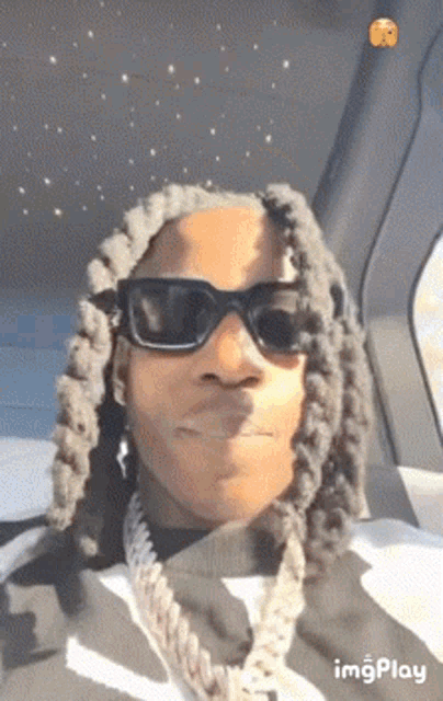 a man wearing sunglasses is sitting in a car .