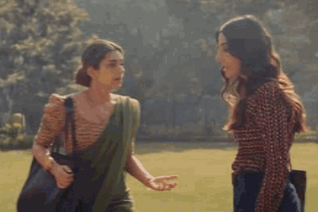 a couple of women are hugging each other in a park .