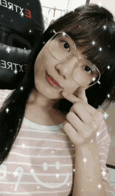 a girl wearing glasses and a shirt with a smiley face on it takes a selfie