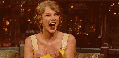a woman is sitting on a couch laughing with her mouth open .