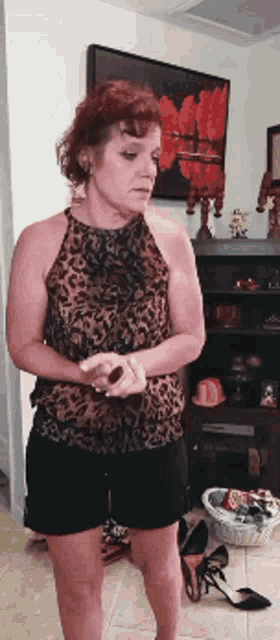 a woman in a leopard print top and shorts stands in a living room