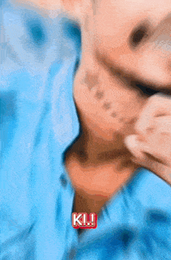 a man in a blue shirt has a tattoo on his face and says ki !!