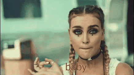 a woman with braids is making a funny face and the word baby is on the bottom .