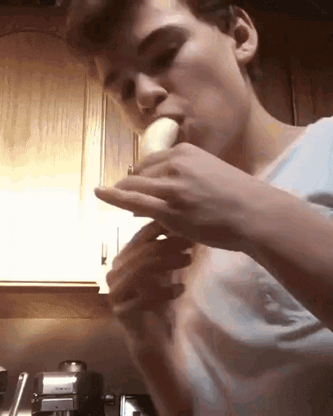 a man eating a banana in a kitchen with a keurig coffee maker in the background