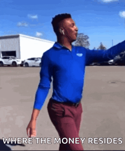 a man in a blue shirt and red pants is dancing in a parking lot with the words where the money resides above him .