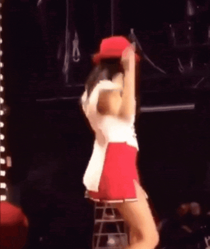 a woman in a red hat and shorts is dancing on a stage .