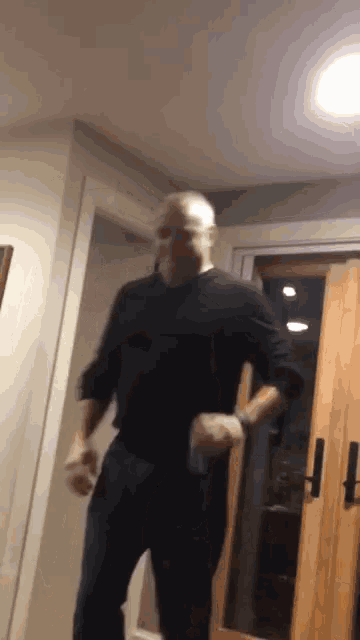 a man in a black shirt is dancing in front of a door