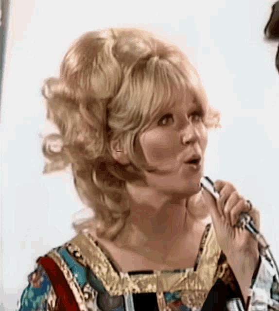 a woman singing into a microphone with a surprised expression on her face