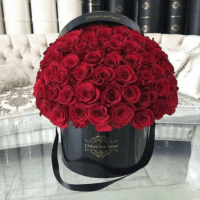 a black box filled with red roses that says j'adore les fleurs on it