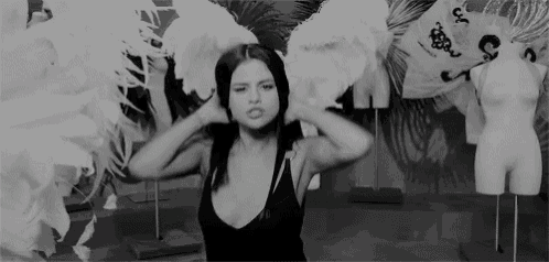 a woman in a black tank top is standing in front of a mannequin .