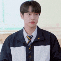 a young man wearing a jacket and tie is standing in a room .