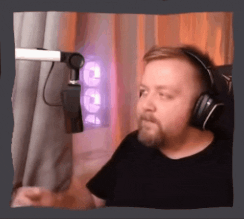 a man with a beard wearing headphones stands in front of a microphone