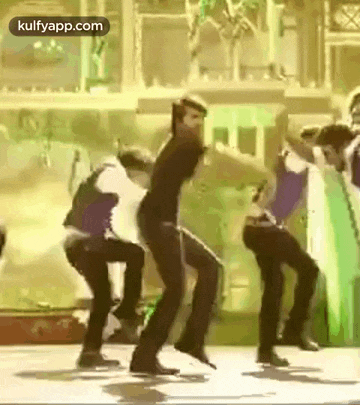 a group of people are dancing together on a stage in front of a building .