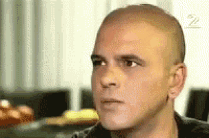 a close up of a man 's face with a shaved head .