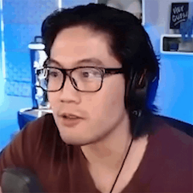 a man wearing glasses and headphones has a sign that says hot cuts in the background