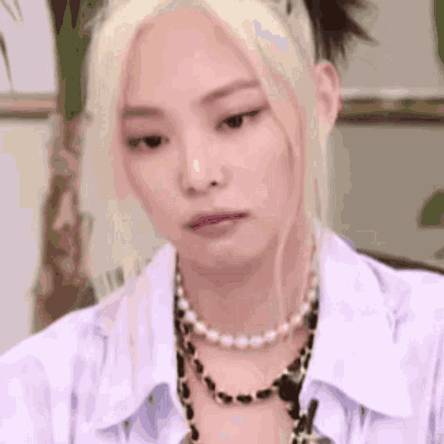 a close up of a woman wearing a white shirt and a necklace .