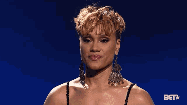 a woman wearing earrings is standing in front of a bet star