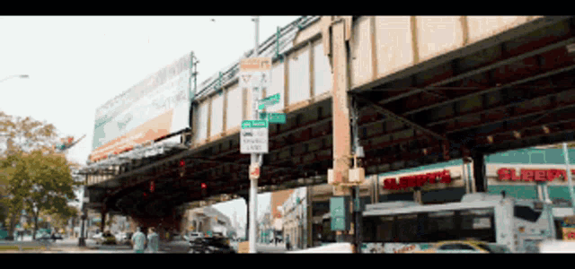 a bus is driving under a bridge next to a store called sleepy 's