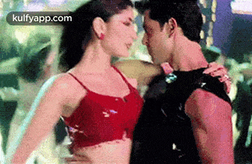 a man and a woman are dancing together in a club and the woman is wearing a red bra .