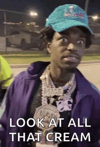 a man wearing a purple jacket and a blue hat says " look at all that cream "