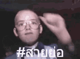 a man wearing glasses and a suit is making a funny face and giving the middle finger .