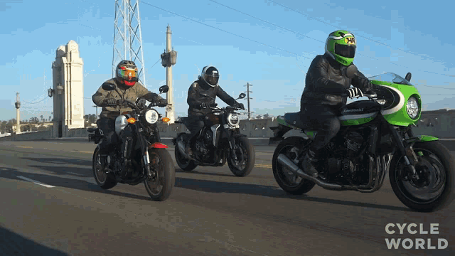 three men are riding kawasaki motorcycles on the road