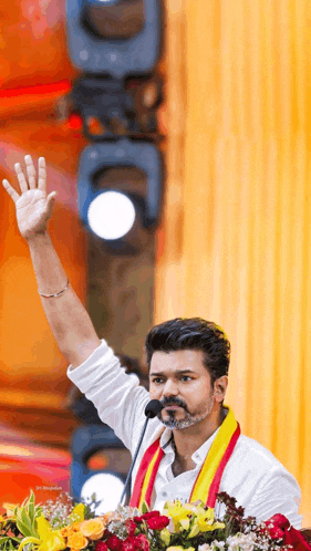 a man is giving a speech in front of a microphone and waving his hand