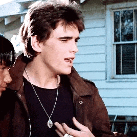 a young man wearing a necklace and a leather jacket is standing next to another man .