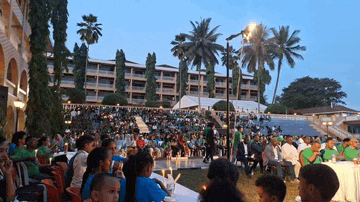 a large group of people are sitting in a stadium in front of a hotel