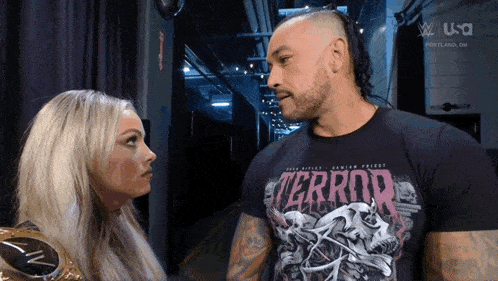 a man and a woman are looking at each other and the man is wearing a terror shirt