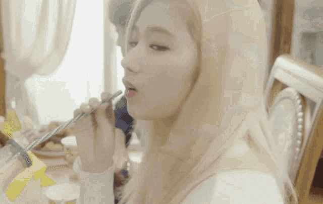 a woman with blonde hair is blowing bubbles with a straw in her mouth .