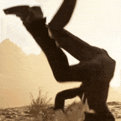 a man in a suit does a handstand in the desert