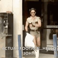 a man dressed as a police officer is standing in front of a building holding a bag of trash .